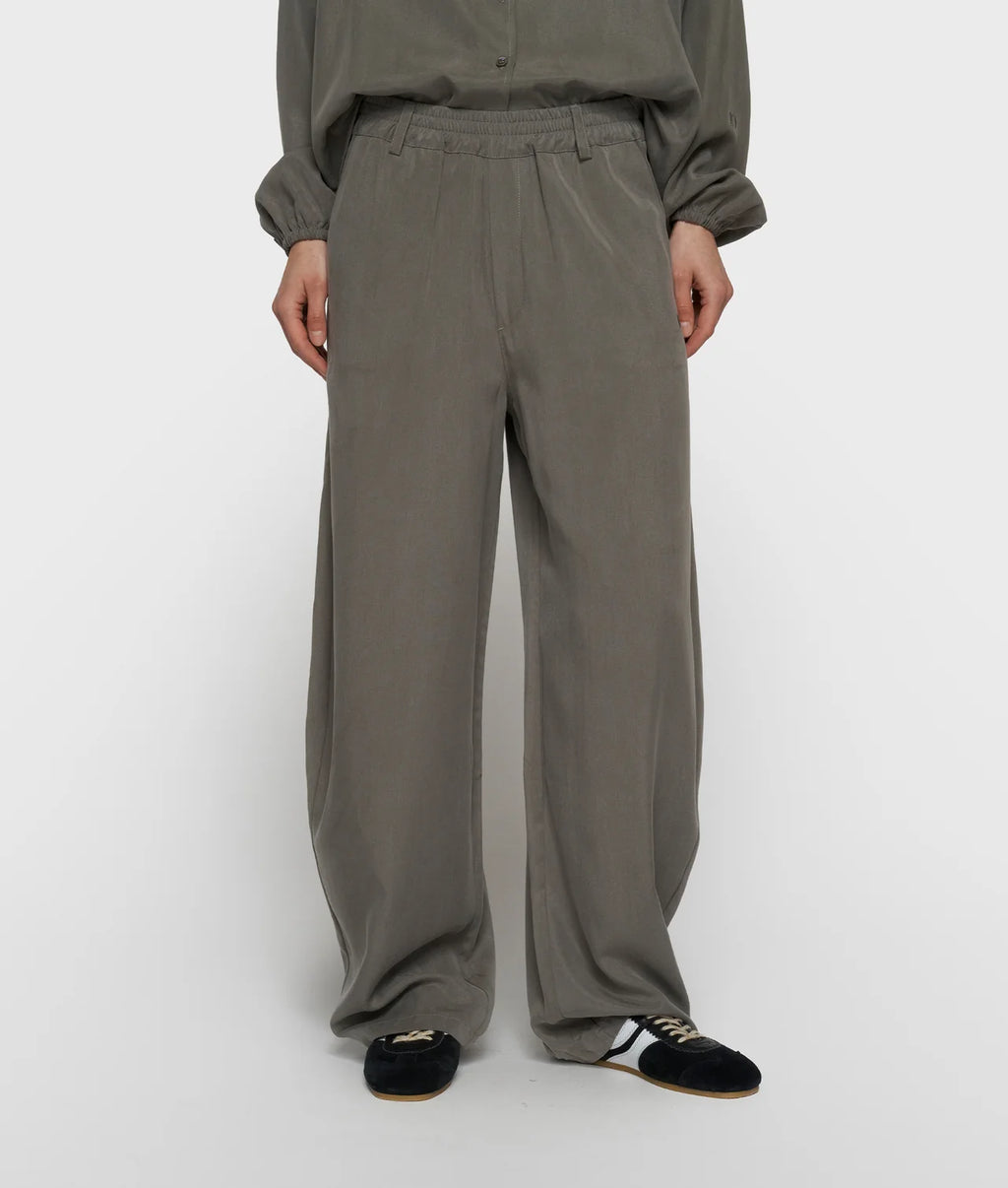 Pantalón de pernera ancha en color topo, llevado con una camisa a juego.