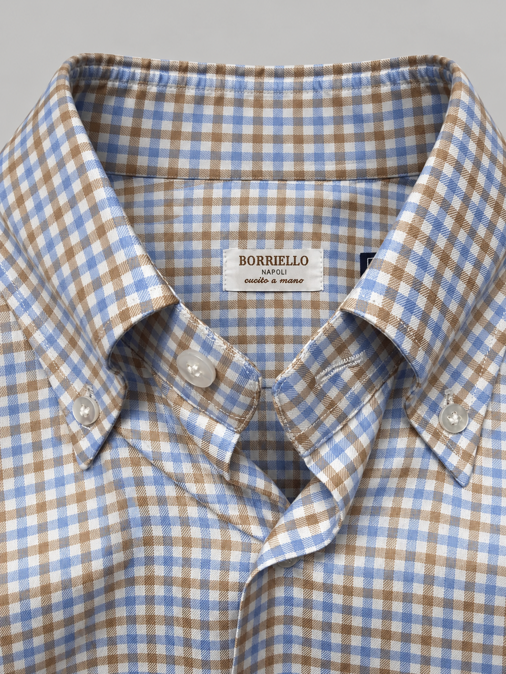Primer plano del cuello y el tejido vichy azul y camel de la camisa Borriello